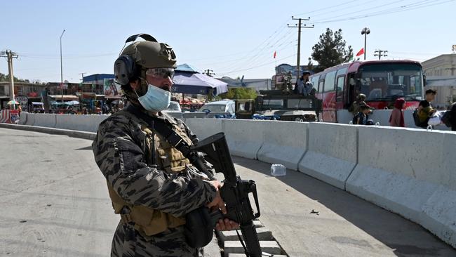 A Taliban Badri fighter, a "special forces" unit, stands guard as Afghans walk to the main entrance gate of Kabul airport on August 28. Their being closely watched by US Marines overseeing the evacuation. Picture: AFP