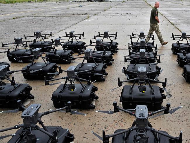 A military operator walks past DJI Matrice 300 reconnaissance drones, bought in the frame of the program 'The Army of Drones' set up ready for test flights in the Kyiv region on August 2, 2022, prior to being sent to the front line. - 'The Army of Drones' is a project initiated by the General Staff of the Armed Forces and the Ministry of Digital Transformation which is a comprehensive program in which organisation purchases drones, repair them, and train operators. (Photo by Sergei SUPINSKY / AFP)