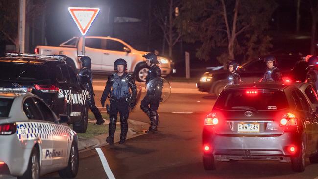 Dozens of police some in riot gear walk through traffic in Taylors Hill. Picture: Jason Edwards