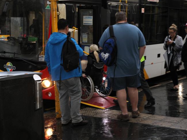 Commuters boarding a bus in the city after a momentary easing of the rain. Picture: Emma Brasier