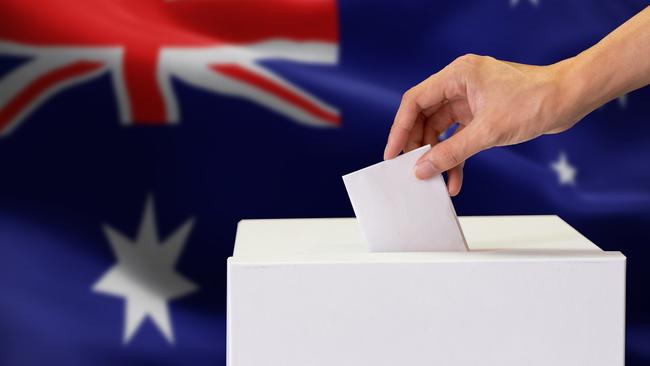 Close-up of human hand casting and inserting a vote and choosing and making a decision what he wants in polling box with Australia flag blended in background