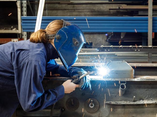 Young Female Welder Working In Factory Wearing Protective Safety Gear  Australian manufacturing workers generic, blue collar