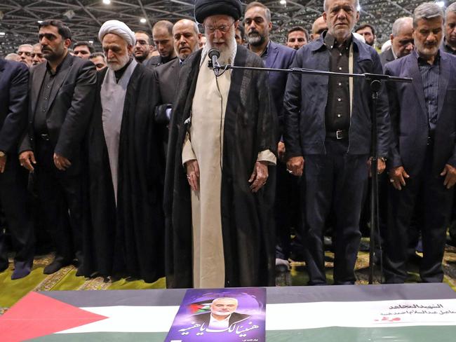 TOPSHOT - A handout picture provided by the Iranian supreme leader Ayatollah Ali Khamenei office shows him (C) leading the prayer, next to Iranian President Masoud Pezeshkian (C-R), over the coffin of late Hamas leader Ismail Haniyeh and his bodyguard, during his funeral procession in Tehran on August 1, 2024, ahead of his burial in Qatar. Iran held funeral processions with calls for revenge after the killing in Tehran of Hamas political chief Ismail Haniyeh in a strike blamed on Israel. (Photo by IRANIAN SUPREME LEADER'S WEBSITE / AFP) / === RESTRICTED TO EDITORIAL USE - MANDATORY CREDIT "AFP PHOTO / HO / IRANIAN SUPREME LEADER'S WEBSITE" - NO MARKETING NO ADVERTISING CAMPAIGNS - DISTRIBUTED AS A SERVICE TO CLIENTS ===