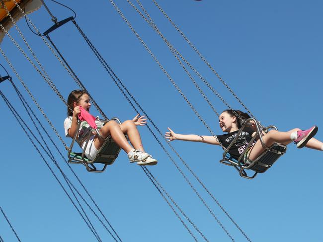 All the fun at the Gold Coast Show, big crowds flock to Sideshow Alley on the first day.Locals  Sian Shroter 9 and Mamie Sabelja 9 tryand hold hands on the Chair O Plane.   Picture Glenn Hampson