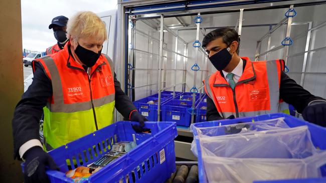 British Prime Minister Boris Johnson, left, and Chancellor Rishi Sunak load a delivery van with trays of shopping at a Tesco distribution centre in London on Thursday. Picture: AFP