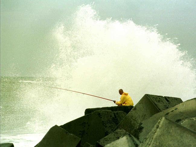 1999. A fisherman dodging the spray from large waves at the southern wall of the Gold Coast Seaway.