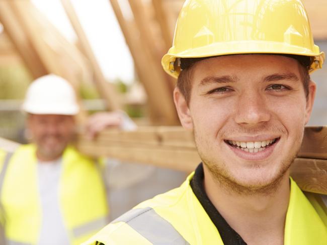 Builder and apprentice carrying wood on construction site.Source: iStock / Getty Images