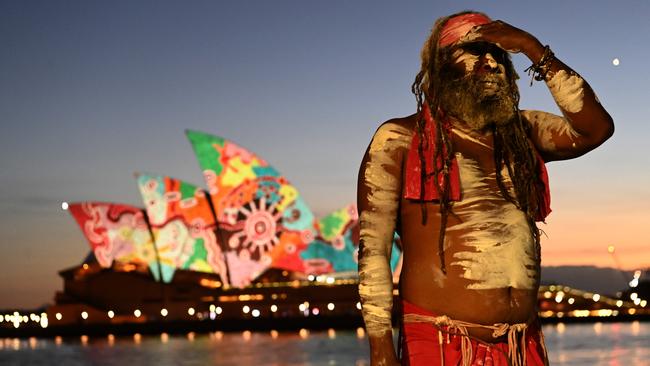 Koomurri performer Les Daniels stands on the foreshore of Campbell’s Cove as Western Desert artist and elder Yadjidta David Miller’s artwork was projected onto the Sydney Opera House at dawn on Australia Day. Picture: NCA NewsWire / Jeremy Piper