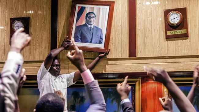 People remove the portrait of former Zimbabwean President Robert Mugabe after his resignation in Harare. Picture: AFP.