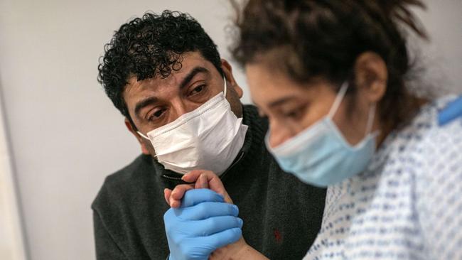 COVID-19 patient and Guatemalan asylum seeker Zully is comforted by her husband Marvin, also Covid-positive after she arrived home by ambulance. Picture: AFP.