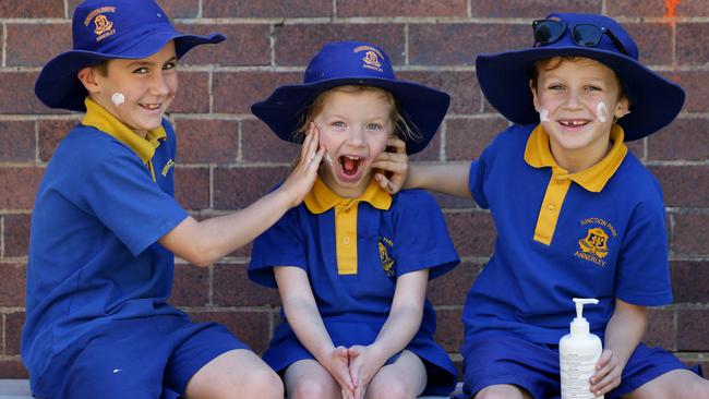 Junction Park State School students Sam Windels, Edith O'Brien and Gianni Seminara apply sunscreen. Picture: Mark Calleja/AAP