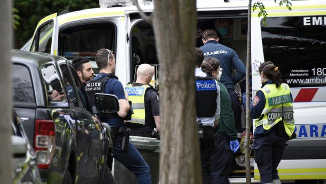 Paramedics attend to a man at Cluden Street East Brighton. Picture: Andrew Henshaw