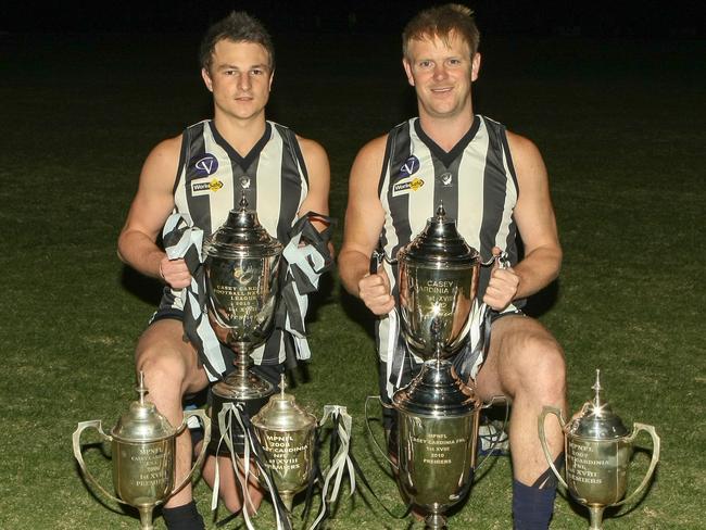 Narre Warren players Nick Scanlon and Michael Collins with their club’s MPNFL Casey-Cardinia premiership cups from 2006, 2007, 2008, 2010, 2012 and 2013. Picture: David Trend