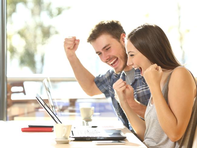 Group of two young euphoric students watching exam results in a laptop in a table of an university campus bar istock image