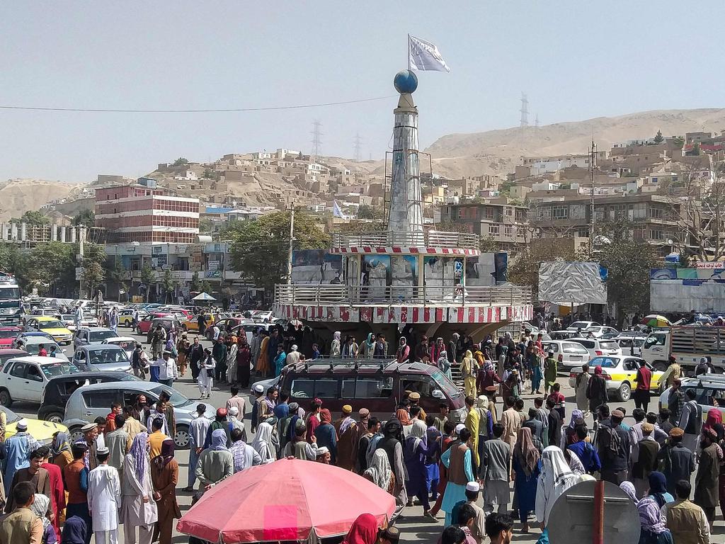 A Taliban flag is seen on a plinth with people gathered around the main city square at Pul-e-Khumri. Picture: AFP