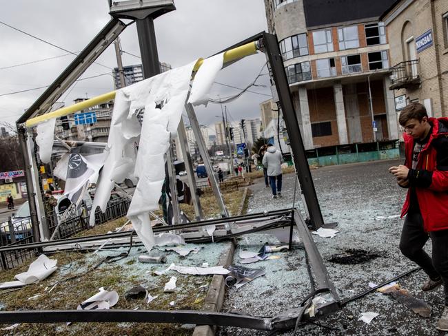 People stand around a damaged structure caused by a rocket in Kyiv.