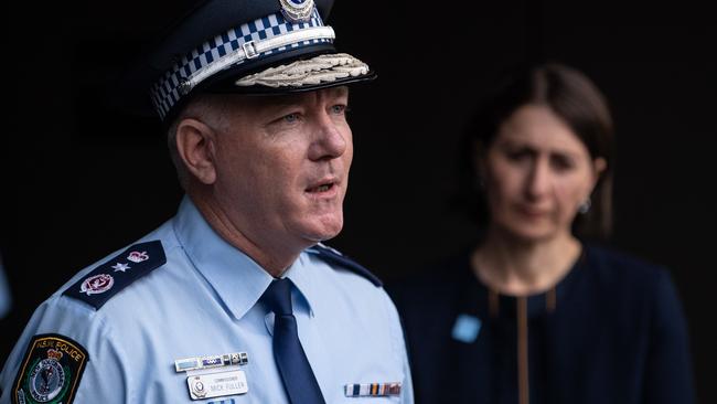 Blue-stickered Gladys Berejiklian watches her chief boy-in-blue, NSW Police Commissioner Mick Fuller, as he speaks to the media last Friday. Picture: AAP