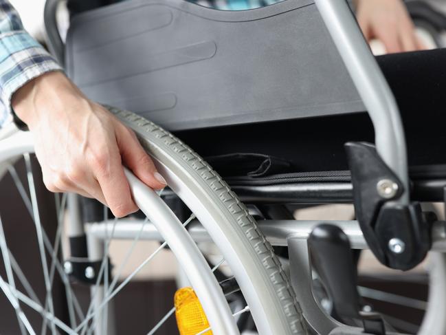 DISABILITY/ DISABLED/ IMPAIRMENT -  Disabled woman sitting in wheelchair and holding on to wheel closeup. Rehabilitation of people with disabilities concept