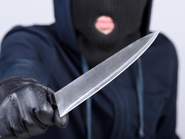 Masked man aims with knife. on gray background. Robbery, crime, knife generic