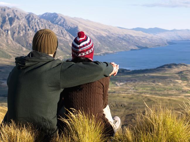 "Hikers admiring scenic view from hilltop, Queenstown, South Island, New Zealand"