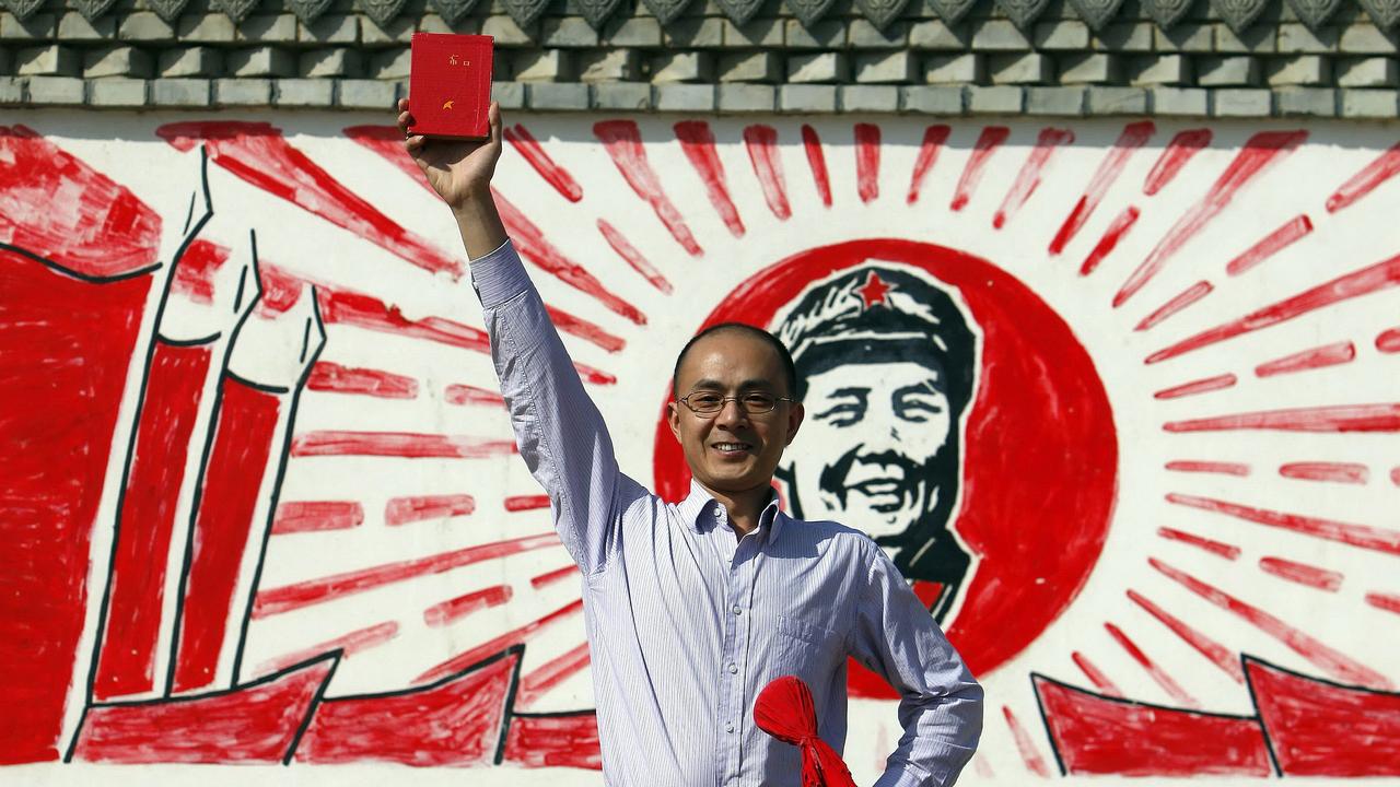 A Chinese visitor proudly holds up a Communist revolutionary 'Red Book' containing the teachings of Mao Zedong, as he poses near a Cultural Revolution rehabilitation camp in Yinchuan, in northwest China's Ningxia region.