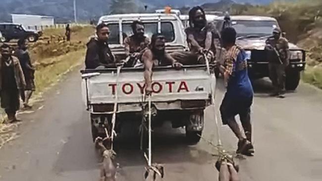 Tribesmen drag the bodies of three killed opponents behind their Toyota ute.