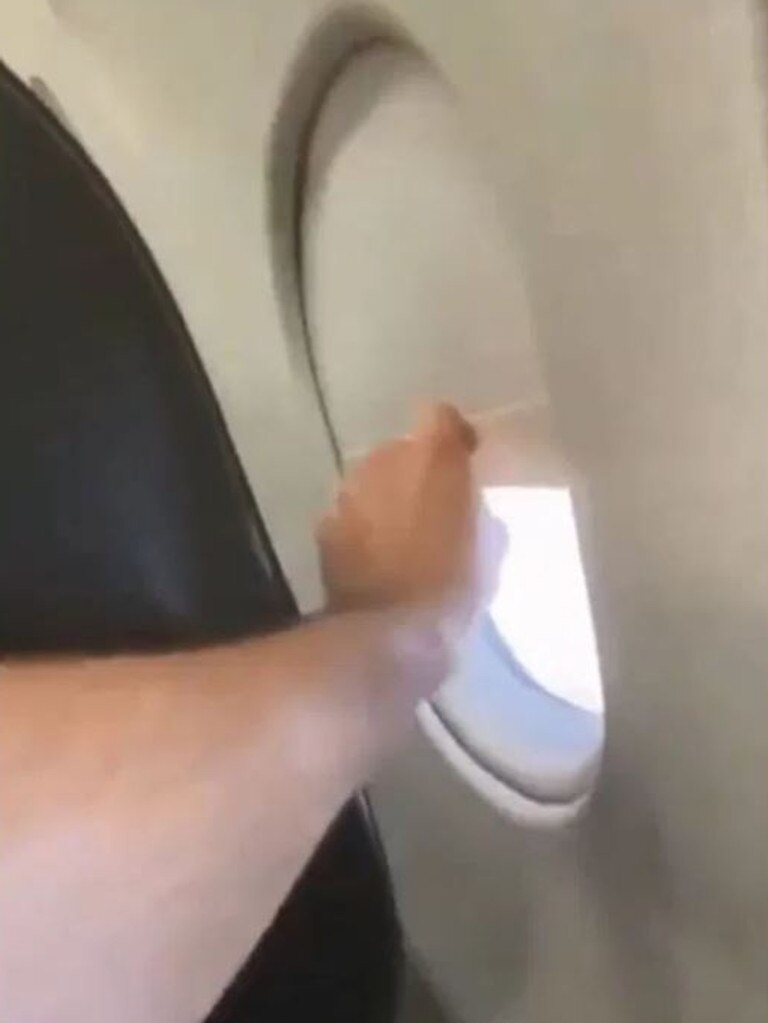 The passenger reaches for the window shade in front of him. Picture: Passenger Shaming