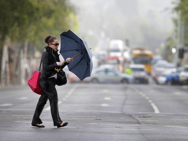 A woman tries to hold her umbrella in the strong winds.