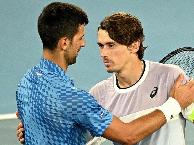 Serbia's Novak Djokovic (L) embraces Australia's Alex De Minaur after their men's singles match on day eight of the Australian Open tennis tournament in Melbourne on January 23, 2023. (Photo by ANTHONY WALLACE / AFP) / -- IMAGE RESTRICTED TO EDITORIAL USE - STRICTLY NO COMMERCIAL USE --