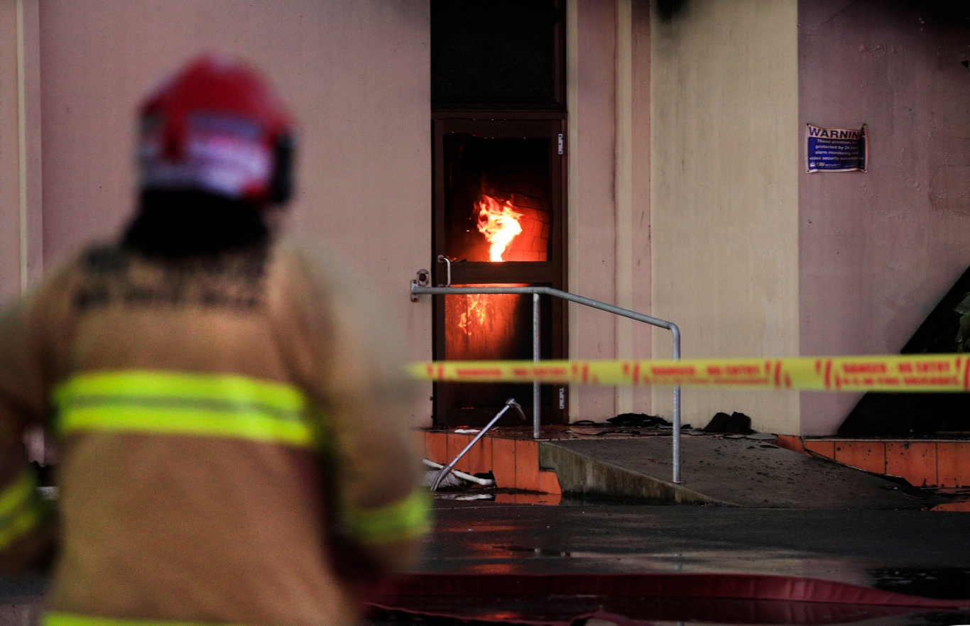 Flames burst from the ground floor of the Cudgen Leagues club as a Queensland Fire Brigade Officer watches on waiting for the arrival of Fire breathing equipment to fight the fire .Photo Scott Powick Newscorp