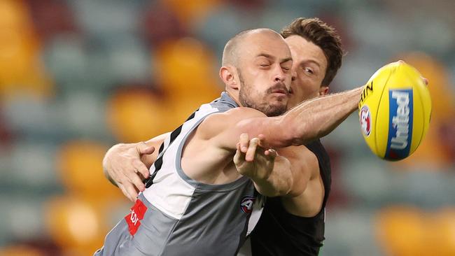 Jarrod Lienert punches away from Collingwood forward Brody Mihocek.