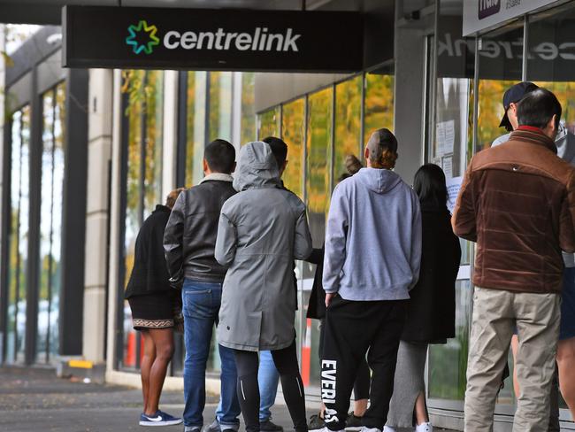 People queue up outside a Centrelink office in Melbourne on April 20, 2020, which delivers a range of government payments and services for retirees, the unemployed, families, carers and parents amongst others. - A report from the Grattan Institute predicts between 14 and 26 per cent of Australian workers could be out of work as a direct result of the coronavirus shutdown, and the crisis will have an enduring impact on jobs and the economy for years to come. (Photo by William WEST / AFP)
