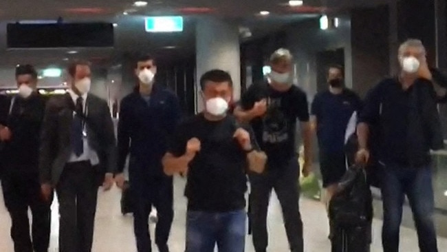 This screen grab taken from AFPTV shows Serbia's Novak Djokovic (3rd L) preparing to depart from Melbourne Airport in Melbourne on January 16, 2022, after losing his legal battle . Picture: Mell Chun/AFP