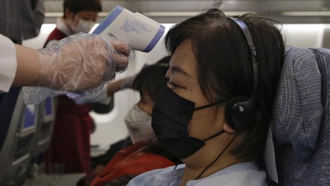 Stewardesses take temperatures of passengers as a preventive measure for the coronavirus on an Air China flight from Melbourne to Beijing on February. 4, 2020. Picture: AP