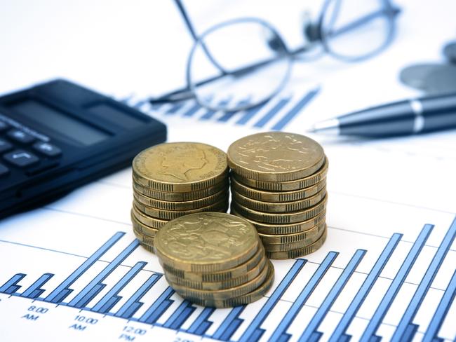 A stack of Australian dollar coins on top of bar charts/graphs. Calculator, pen and glasses (spectacles) in the background. Generic money investing