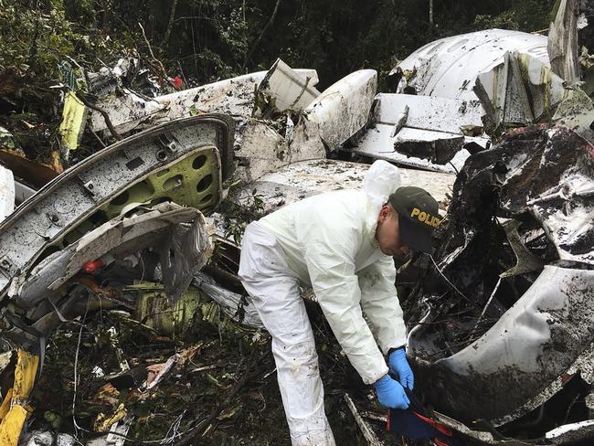 A police officer sifts through the wreckage of the chartered aeroplane that crashed in La Union, outside Medellin, on November 28 local time. Picture: Colombia National Police via AP