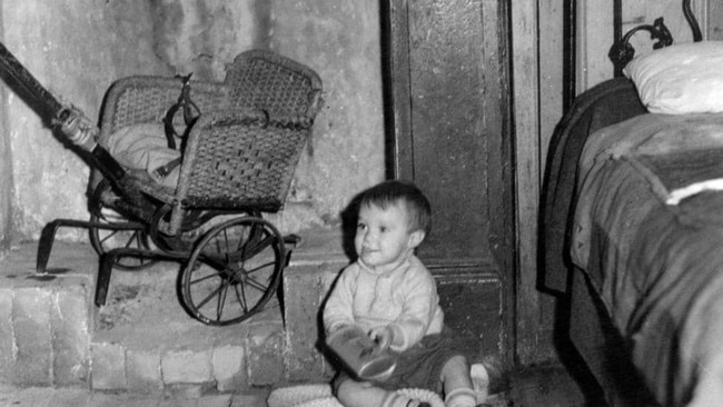 A small child plays on the bare floors. 1936 Picture: Herald Sun Image Library