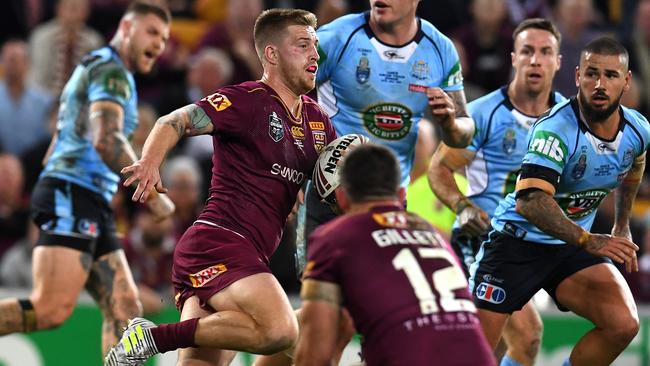 Cameron Munster of the Queensland Maroons (centre) gains ground.