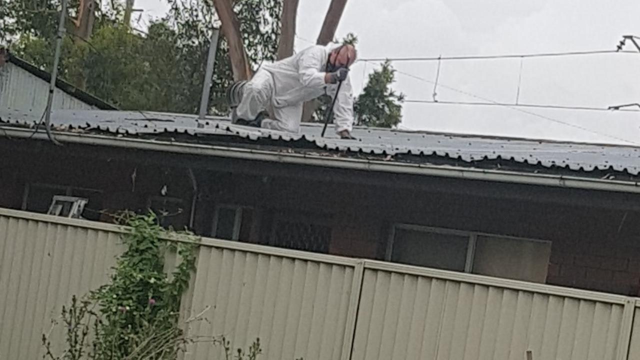 A forensic investigator using a crow bar to peel apart layers of the roof.