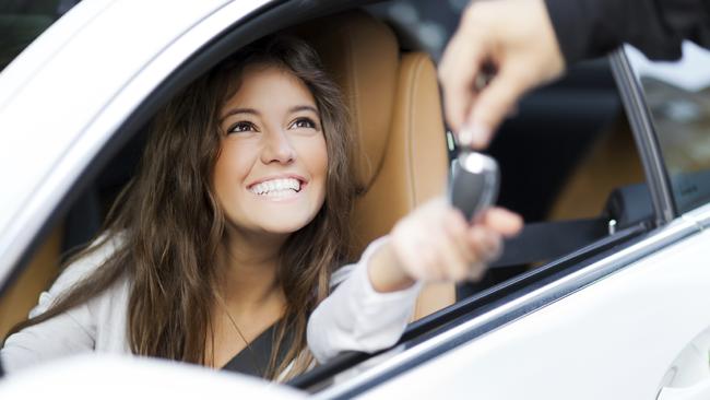 Young woman receiving the keys of her new car