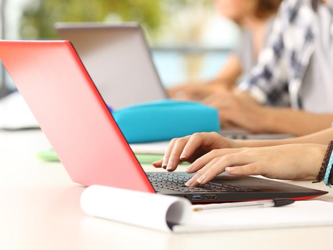 Side view close up of three student hands learning on line typing in their laptops in a classroom