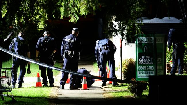 Police look at bullet casings on the ground where a man was shot in the head as he sat in his car at Chester Hill. Picture: Bill Hearne
