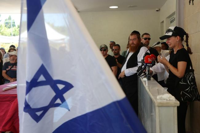 A relative of Yevgeny Ferder, 50, killed in a Yemeni Huthi rebel drone attack on Tel Aviv, speaks next to his coffin during his funeral in Rishon LeZion, Israel