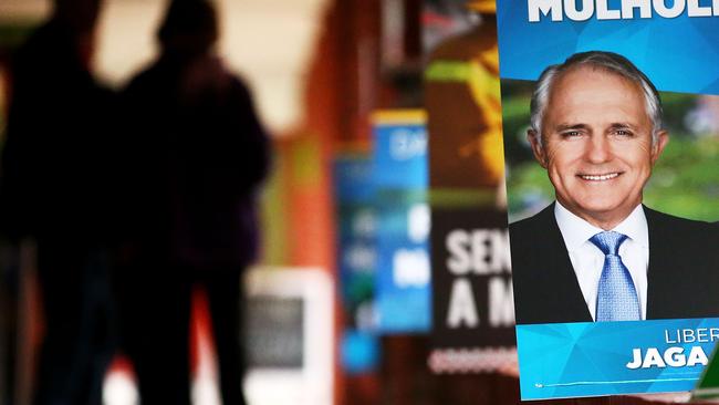 People arrive to vote near a photo of Prime Minister Malcolm Turnbull in Melbourne, Australia. Picture: Scott Barbour