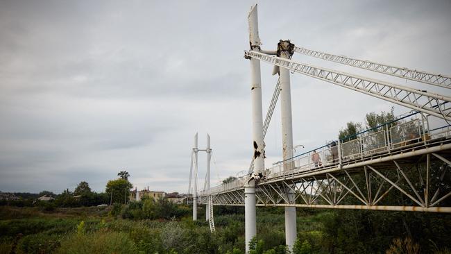 Pedestrians walk on a partially destroyed bridge in Izyum, Kharkiv region.