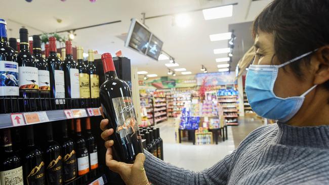 A woman looks at a bottle of Australian wine at a supermarket in Hangzhou, in eastern China's Zhejiang province. Picture: STR / AFP) / China OUT