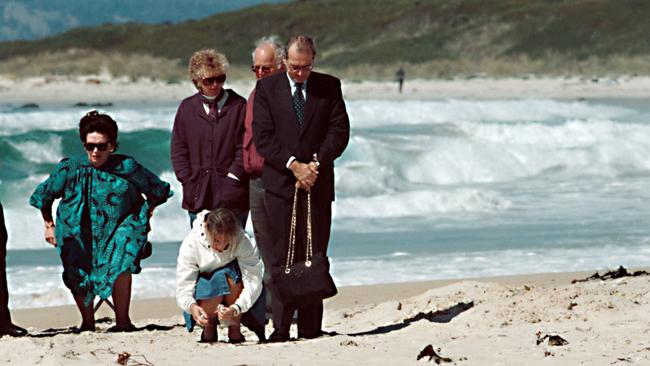 Murder of Victoria Cafasso, 20, on Beaumaris Beach, East Coast of Tasmania, October 1995, Memento of her daughter's death: Mrs Xenia Cafasso scoops up a handful of sand, as husband Guiseppi Cafasso stands silenty beside her. Picture: Drew Fitzgibbon Mercury Archives