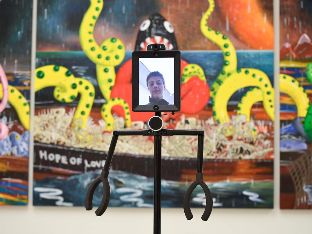 A visitor poses a robot that can be digitally controlled to explore the exhibition remotely during next to an art work during the press preview of 'Philip Colbert: Lobsteropolis' at the Saatchi Gallery in London on October 29, 2020. - Lobsteropolis gives audiences the opportunity to view artwork in person or digitally via robots from the comfort of their own home in an innovation designed to make the exhibition   'lockdown-proof' during the coronavirus pandemic. (Photo by JUSTIN TALLIS / AFP) / RESTRICTED TO EDITORIAL USE - MANDATORY MENTION OF THE ARTIST UPON PUBLICATION - TO ILLUSTRATE THE EVENT AS SPECIFIED IN THE CAPTION