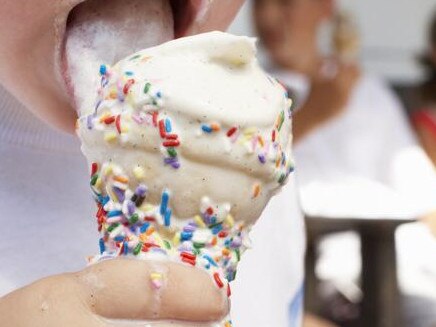 Boy (2-4) licking ice cream, close-up, other children in background