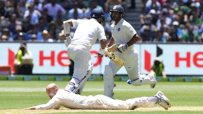 Australian off-spinner Nathan Lyon watches on from the turf as Cheteshwar Pujara (left) and Mayank Agarwal scamper through for runs. Picture: AAP